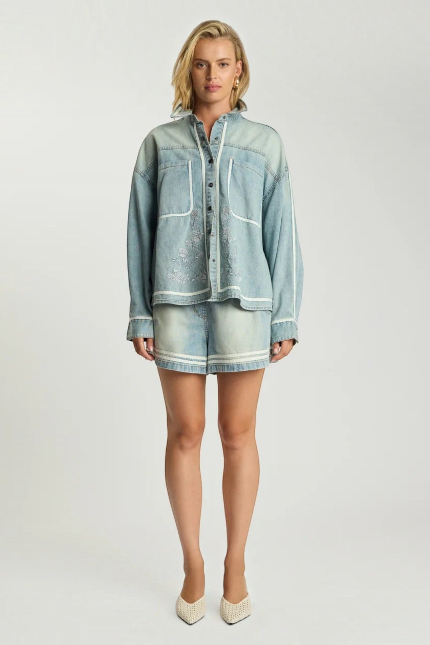 Model wearing ELSHAM BOUTIQUE folklore chambray blue denim shirt and matching high waist flippy shorts with embroidery.