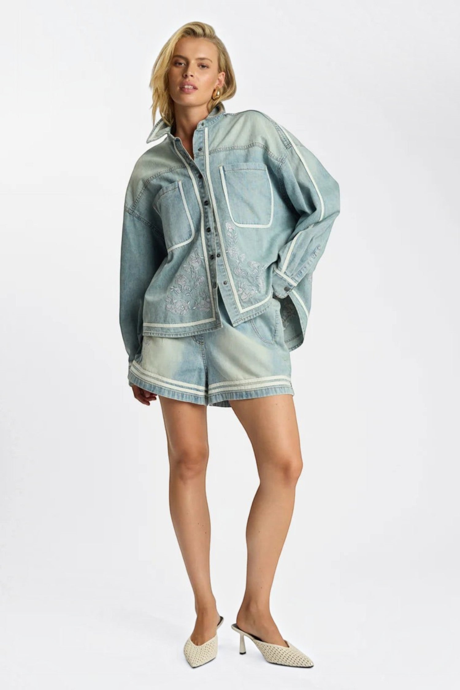 ELSHAM BOUTIQUE model wearing a folklore chambray blue denim shirt and matching high waist flippy shorts with embroidery