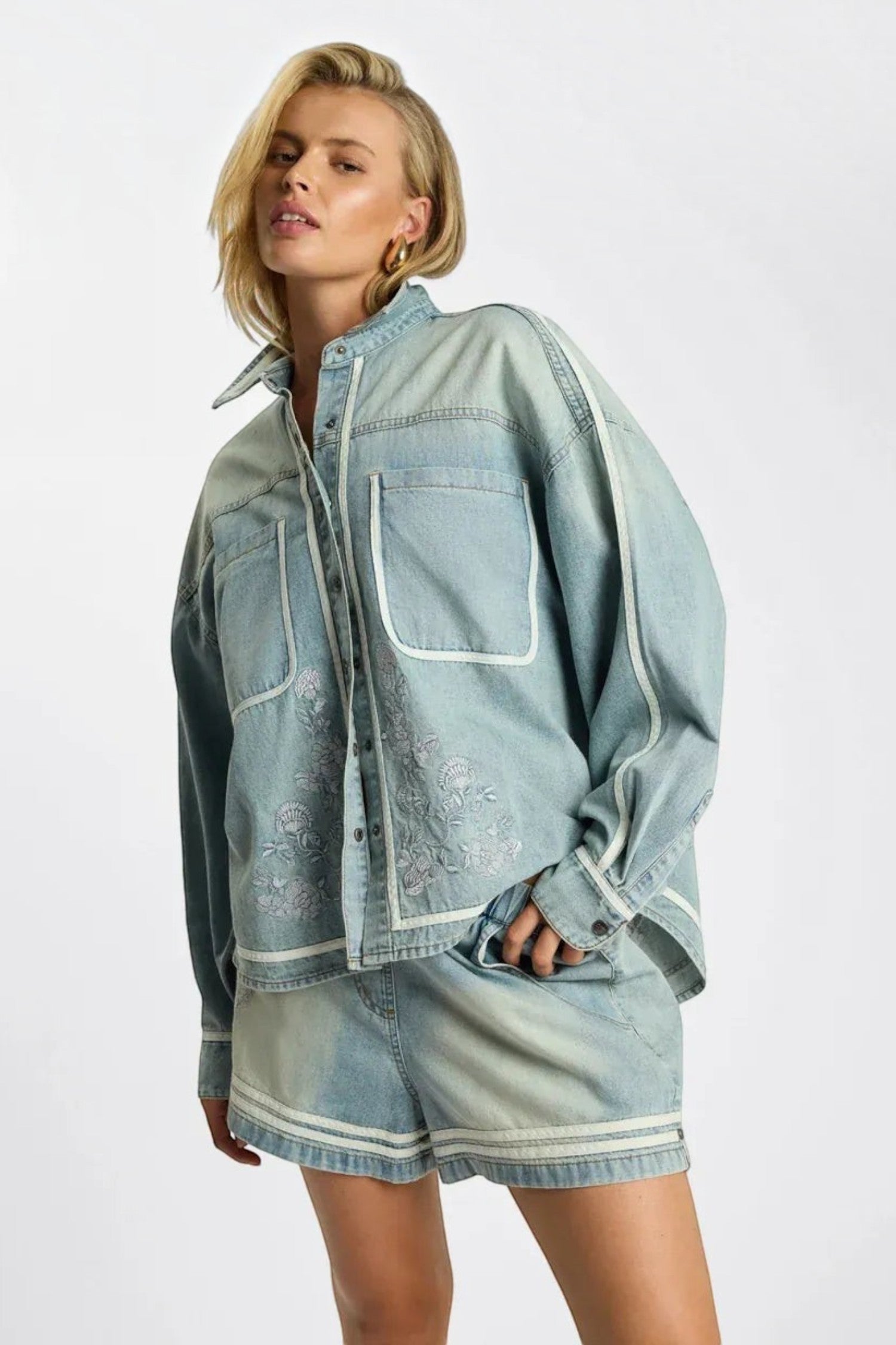 Model wearing ELSHAM BOUTIQUE chambray blue denim shirt with artisan embroidery and white piping detail