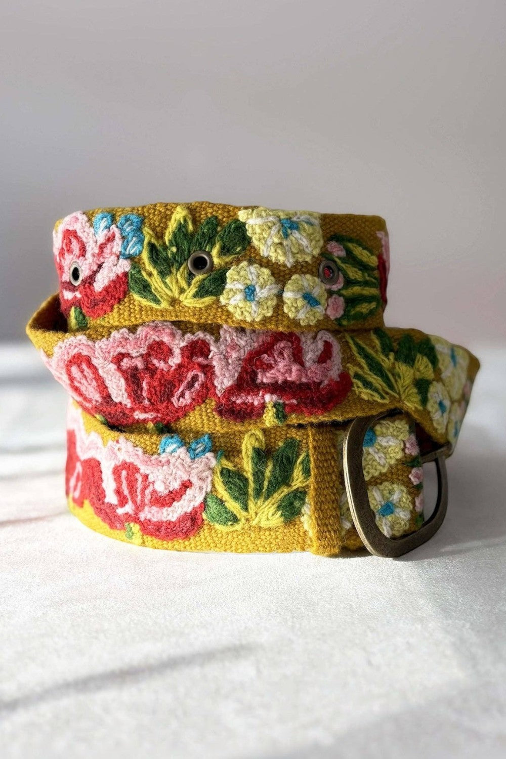 ELSHAM BOUTIQUE Giverny mustard yellow wool belt featuring vibrant floral embroidery and a lead-free metal buckle.