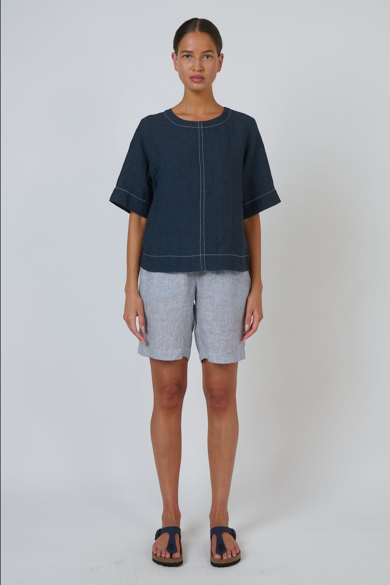 Model wearing ELSHAM BOUTIQUE GA724A Neat Top in gunsmoke linen with contrast white topstitching and short sleeves.