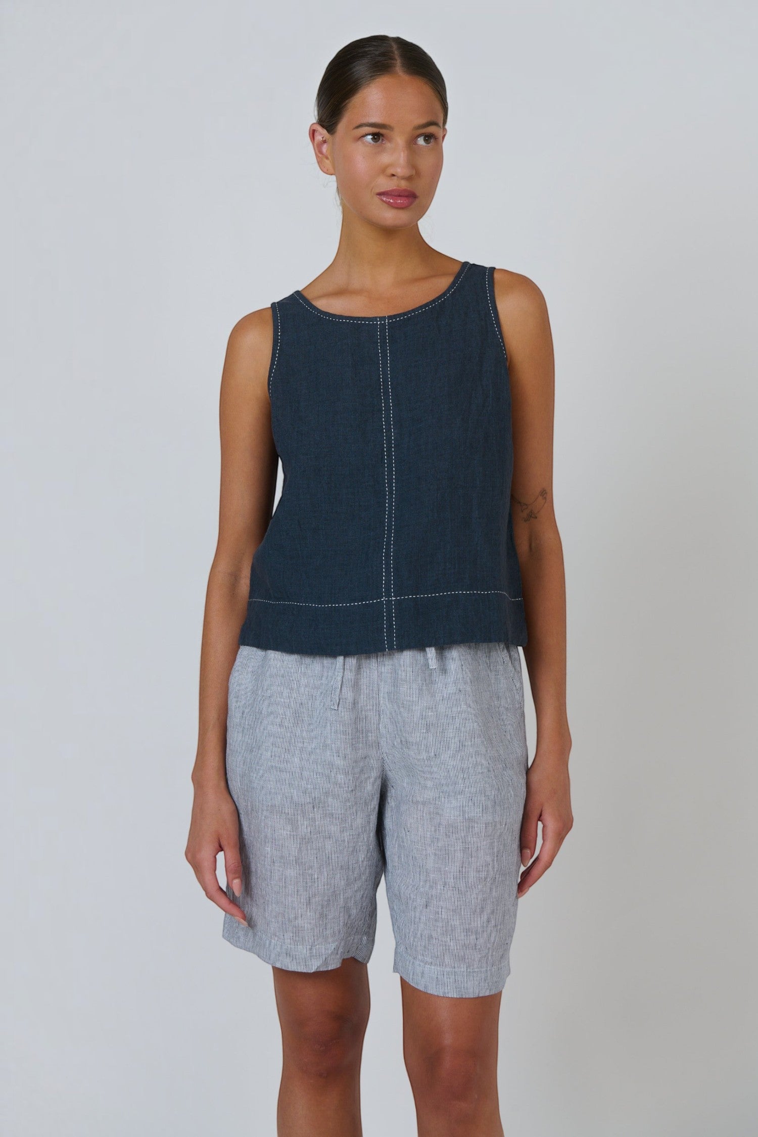 ELSHAM BOUTIQUE sleeveless linen top in gunsmoke grey with white contrast stitching and a relaxed fit on a model.