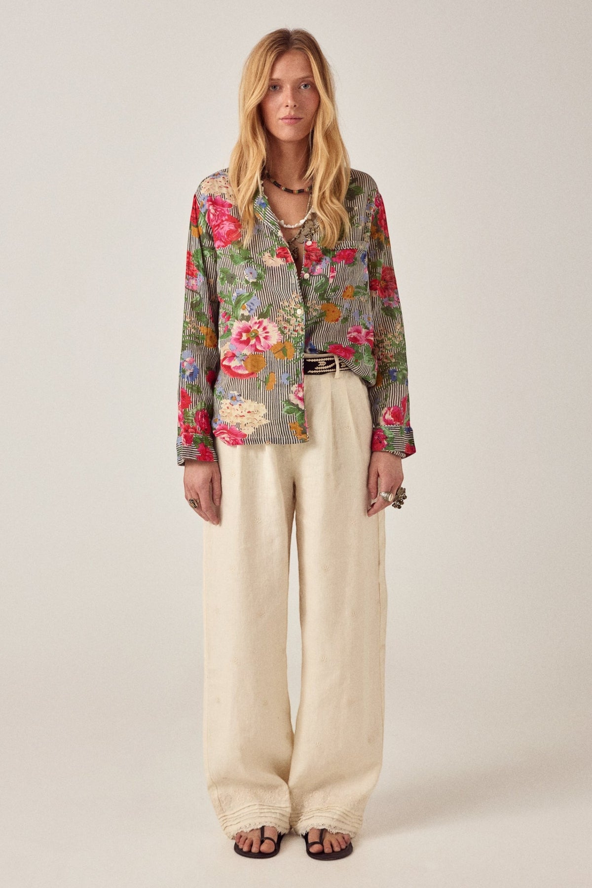 Model wearing ELSHAM BOUTIQUE ivory cotton-linen Otto pants with subtle pleats and embroidered hem details
