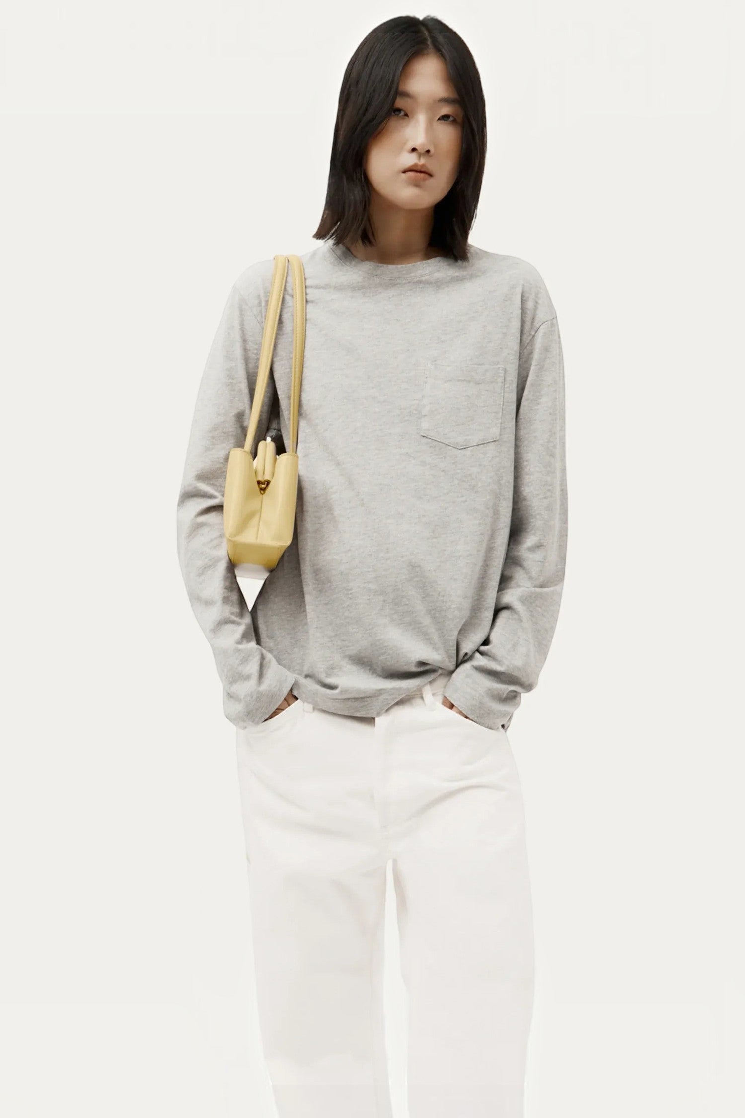 Model wearing an ELSHAM BOUTIQUE Mini Vault Tote in lemonade yellow ironed calf nappa leather with dual top handles.