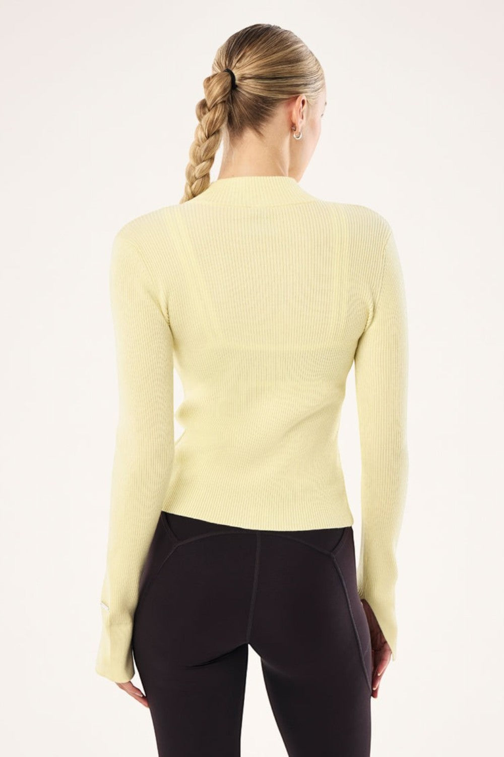 Back view of ELSHAM BOUTIQUE soft yellow rib knit zip jacket with high neck and long sleeves on a model