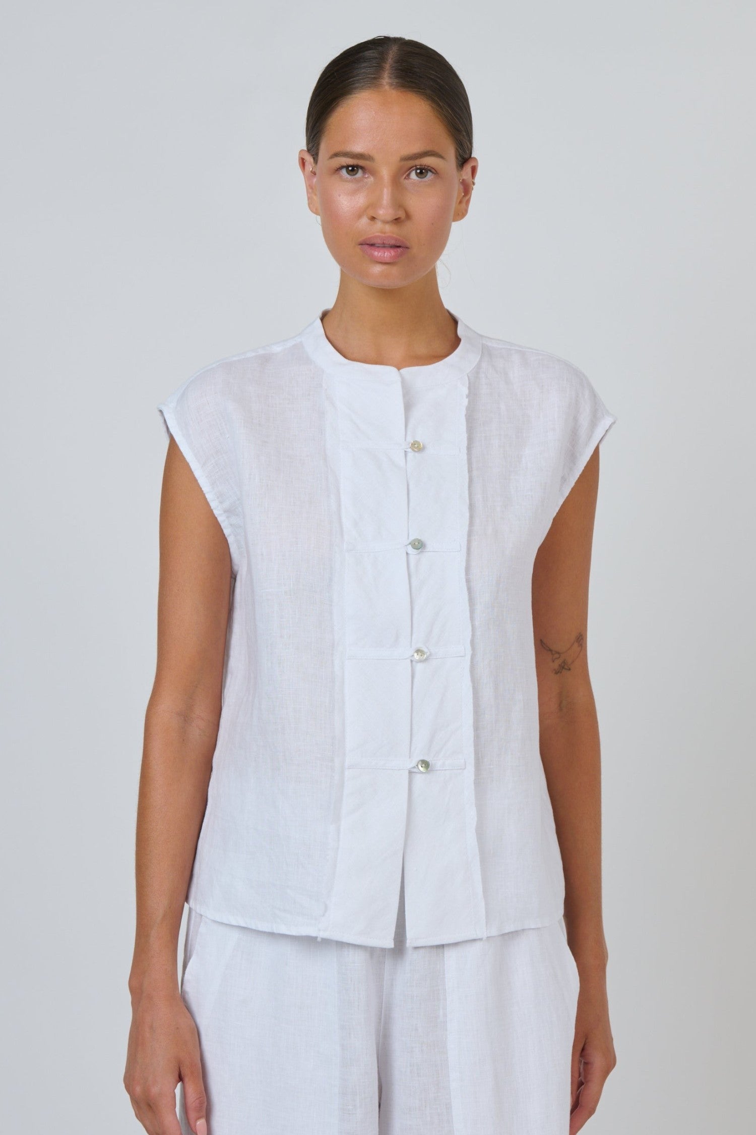 ELSHAM BOUTIQUE white linen sleeveless top with a collarless neckline and quilted button-through placket.