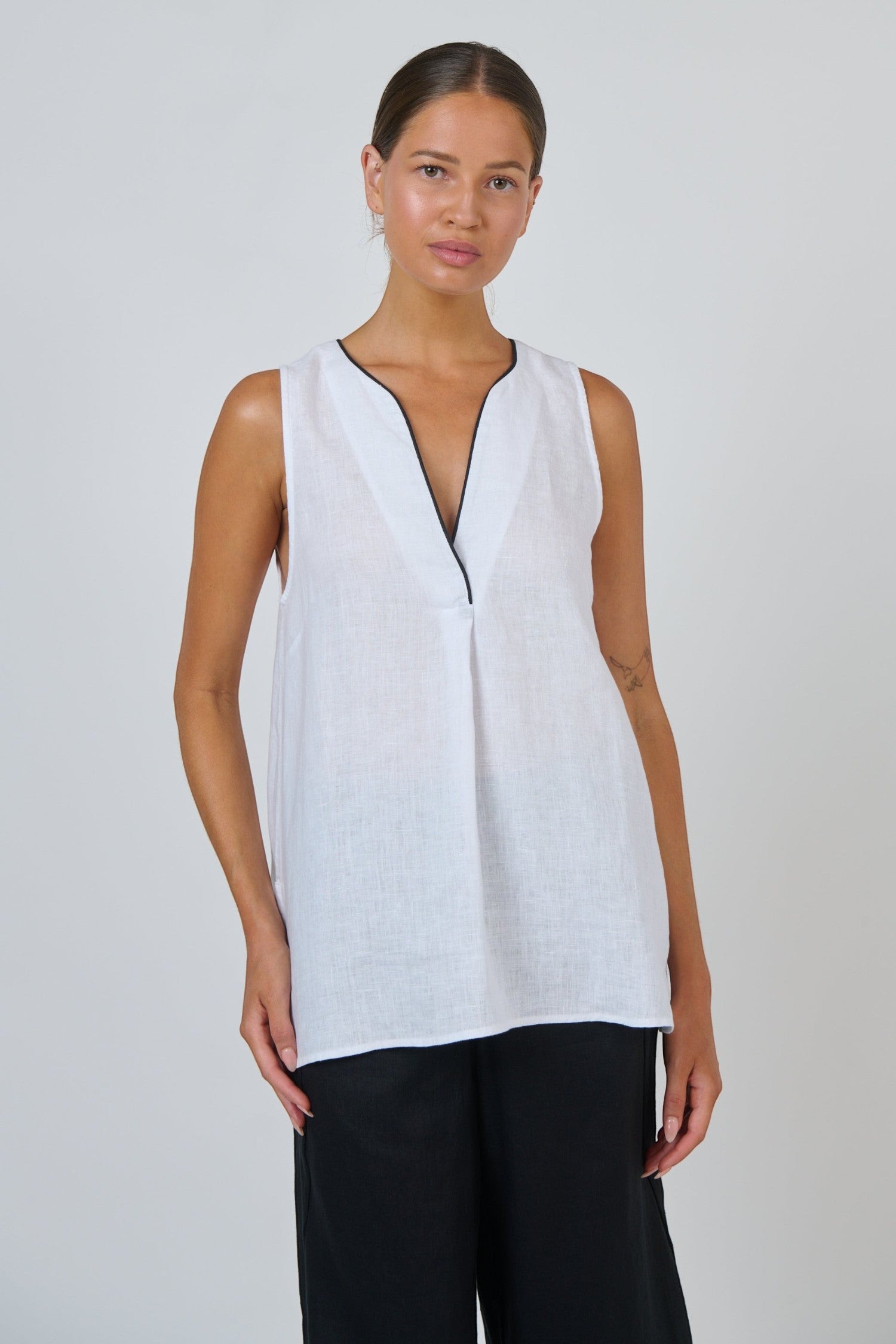 ELSHAM BOUTIQUE white sleeveless linen top with a deep V-neckline and black contrast piping in an A-line silhouette.