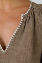 ELSHAM BOUTIQUE agate linen shift dress featuring a V-neckline with white contrast embroidery and gathered shoulders.