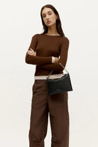 Model wearing ELSHAM BOUTIQUE black calf nappa Siamese bag with gold brass chain handle and adjustable strap