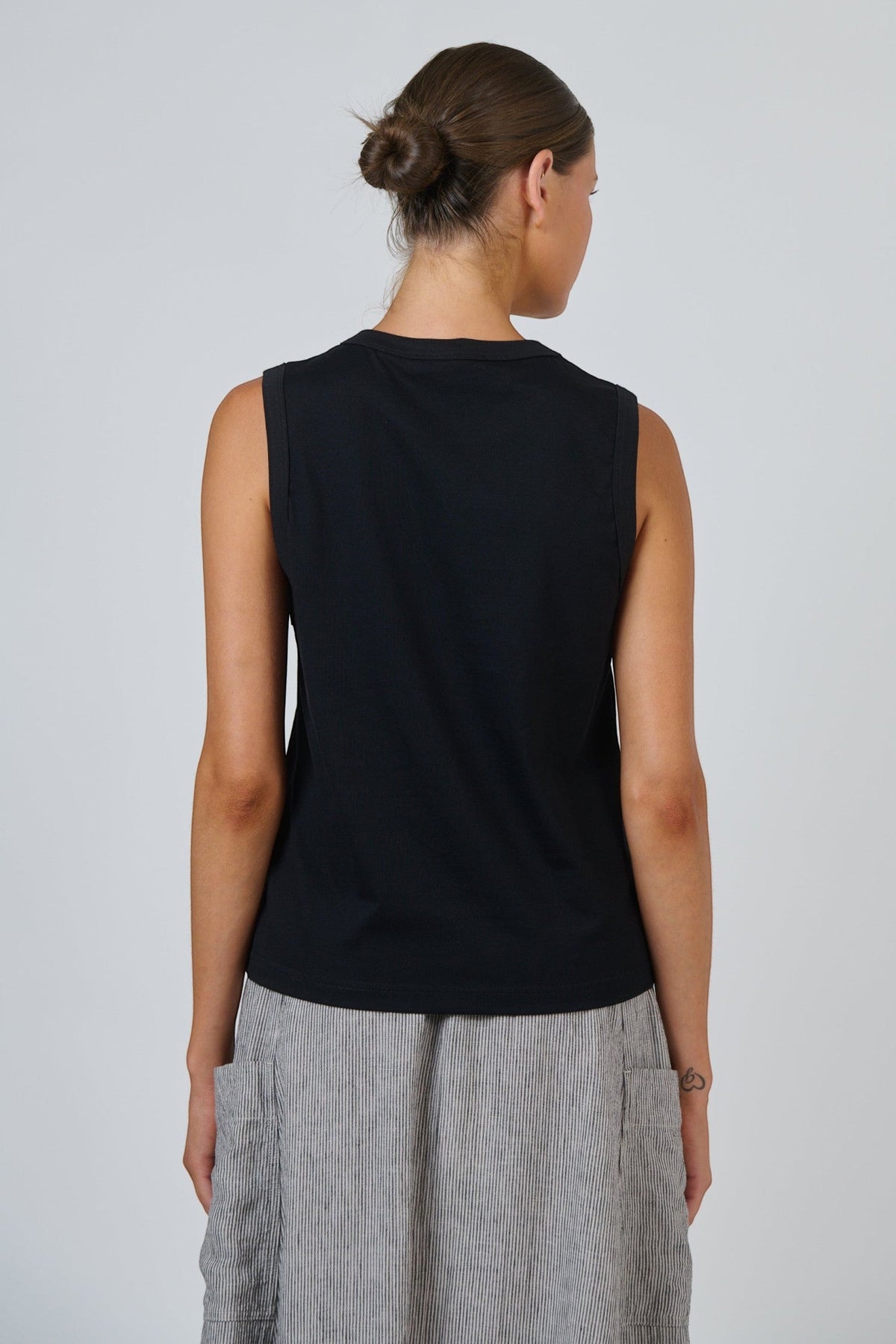 Back view of ELSHAM BOUTIQUE black cotton sleeveless muscle top with a round neckline on a model