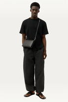 ELSHAM BOUTIQUE black calf nappa leather Siamese bag worn as a crossbody by a male model in a black outfit