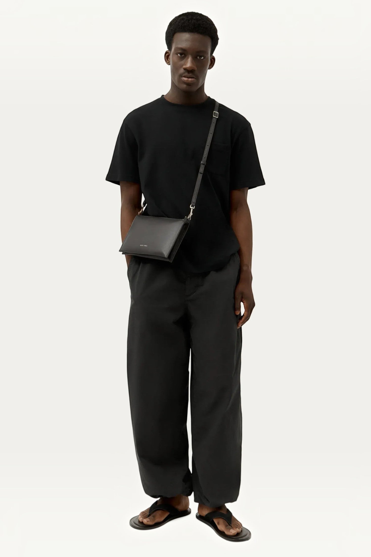 ELSHAM BOUTIQUE black calf nappa leather Siamese bag worn as a crossbody by a male model in a black outfit