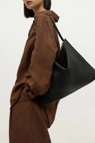 ELSHAM BOUTIQUE Chopalopagus black calf nappa leather slouchy shoulder bag with brass hardware worn by a model