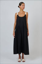 Model wearing ELSHAM BOUTIQUE black poplin maxi dress with contrast buckle straps and a tiered A-line skirt