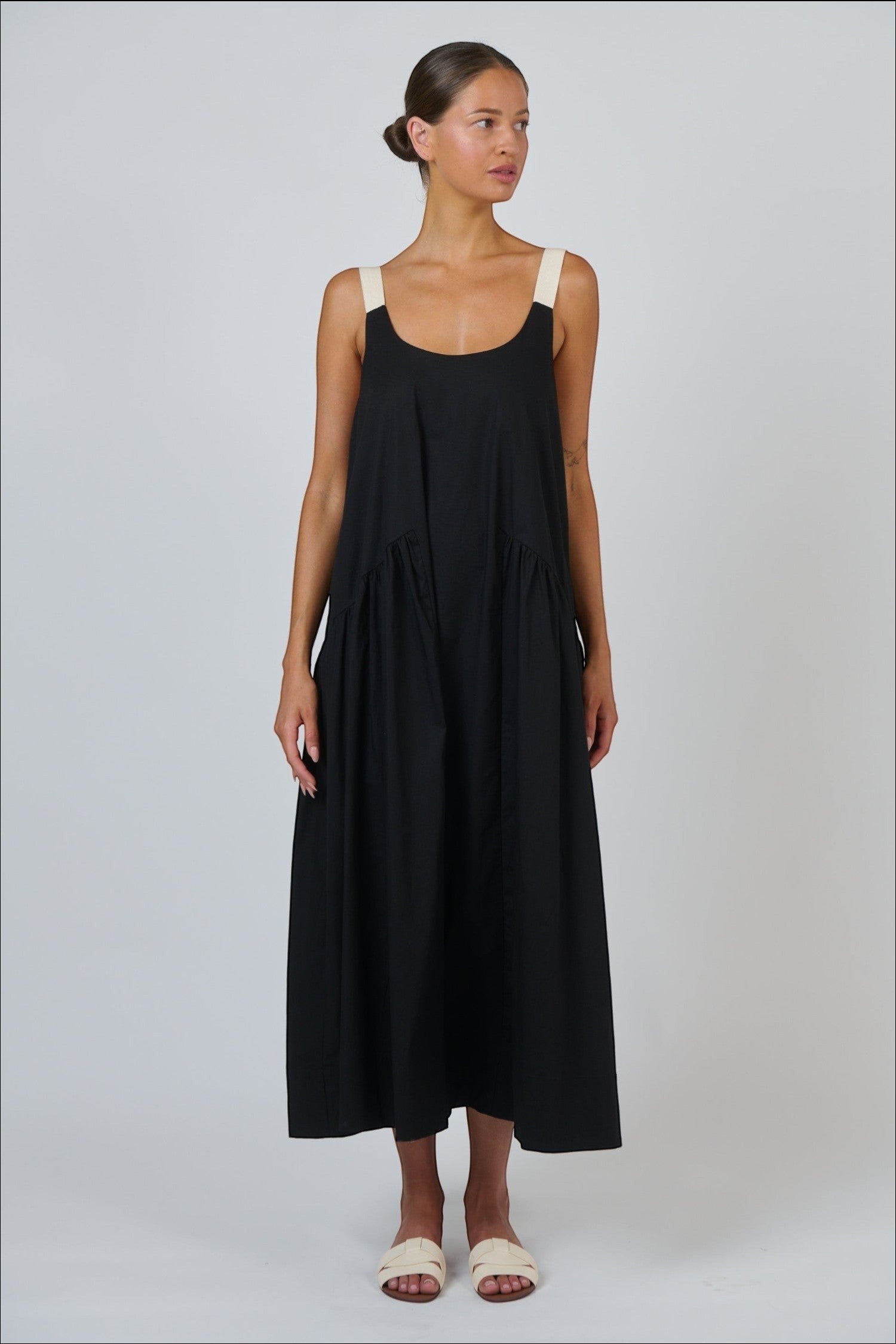 Model wearing ELSHAM BOUTIQUE black poplin maxi dress with contrast buckle straps and a tiered A-line skirt