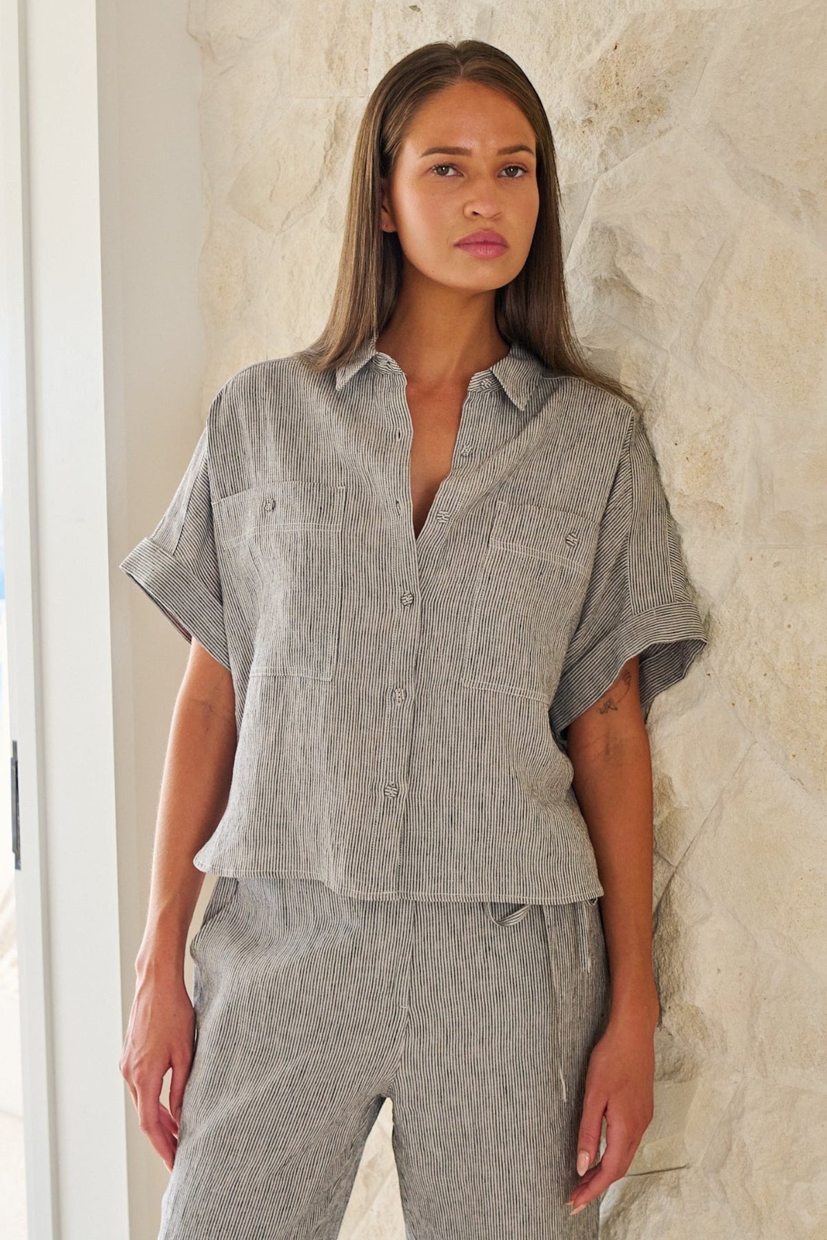 Model wearing ELSHAM BOUTIQUE GA723 boxy linen shirt in grey pinstripe with cuffed sleeves and patch pockets.