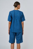 Back view of ELSHAM BOUTIQUE chambray linen blouse with puffed sleeves and gathered back yoke on a model
