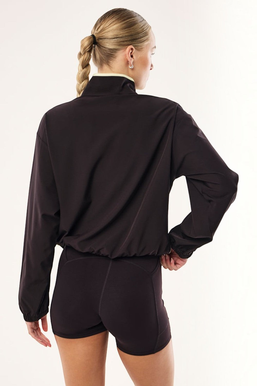 ELSHAM BOUTIQUE Echo black bean quarter zip jacket with adjustable waist drawcords worn by a woman from the back.