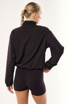 ELSHAM BOUTIQUE Echo black bean quarter zip jacket with adjustable waist drawcords worn by a woman from the back.