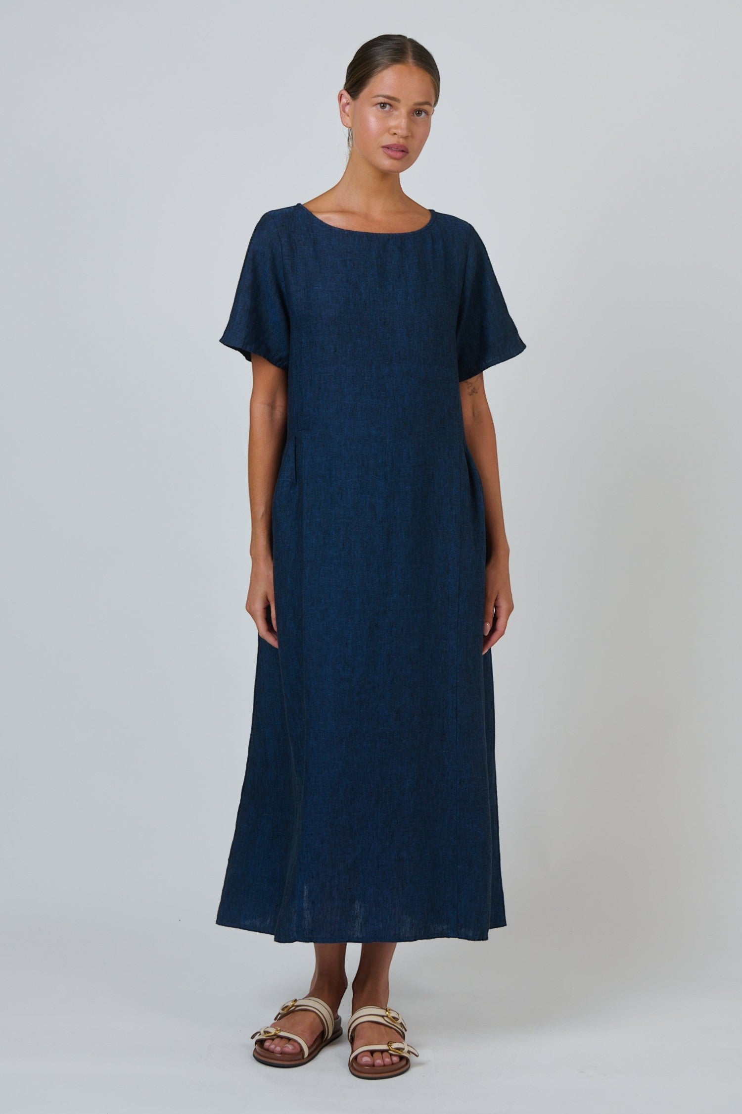 Model wearing ELSHAM BOUTIQUE eclipse blue 100% linen midi dress with scoop neckline and short sleeves.