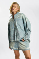 ELSHAM BOUTIQUE model wearing a chambray blue embroidered denim shirt and matching high-waisted flippy denim shorts.