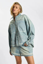 Model wearing ELSHAM BOUTIQUE chambray blue denim shirt with artisan embroidery and white piping detail