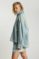 ELSHAM BOUTIQUE chambray blue denim shirt with artisan embroidery, relaxed fit, and long sleeves on a blonde model.