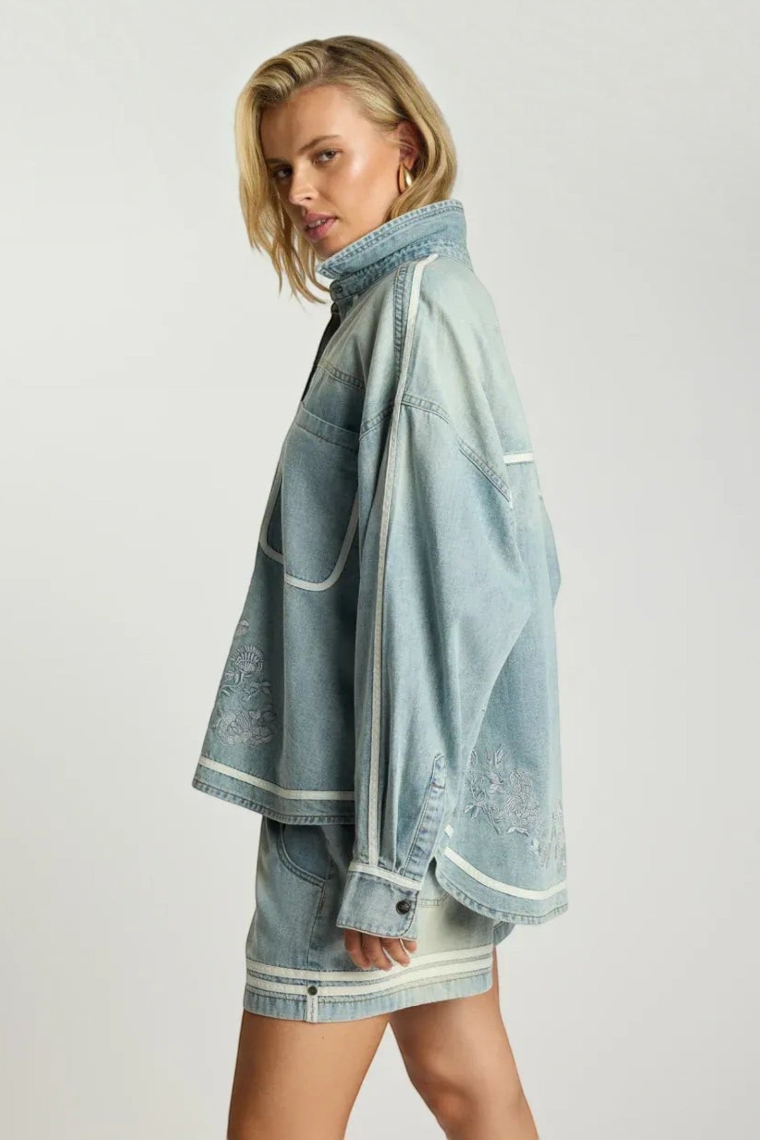 ELSHAM BOUTIQUE chambray blue denim shirt with artisan embroidery, relaxed fit, and long sleeves on a blonde model.