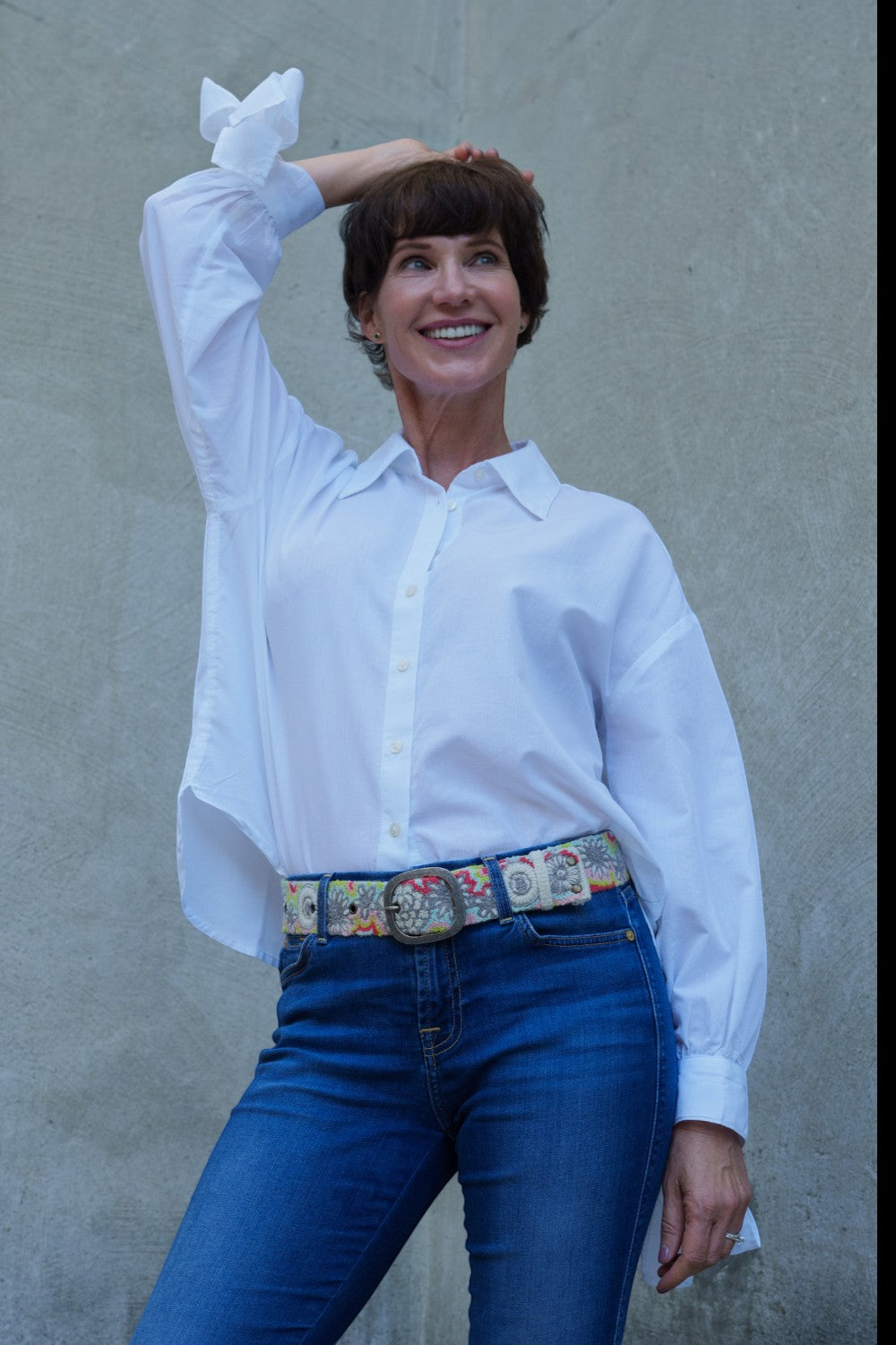 ELSHAM BOUTIQUE wool belt with floral embroidery worn by a woman in a white shirt and blue jeans against a grey wall