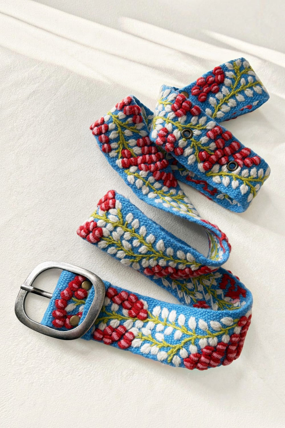 ELSHAM BOUTIQUE wool belt in light blue with red and white embroidered berry vine pattern and metal buckle.