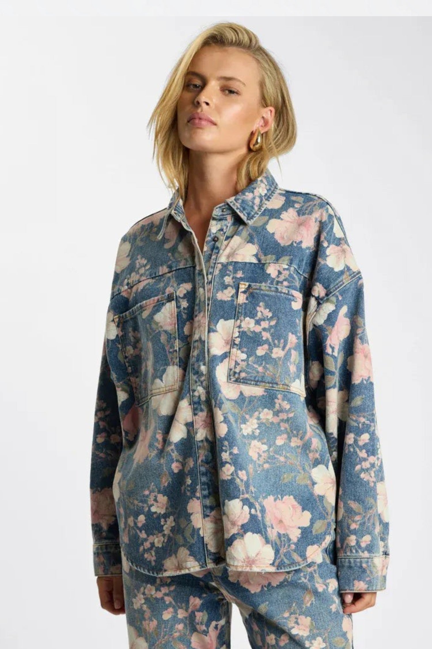 ELSHAM BOUTIQUE oversized blue denim shacket with all-over floral print and silver hardware worn by a blonde model