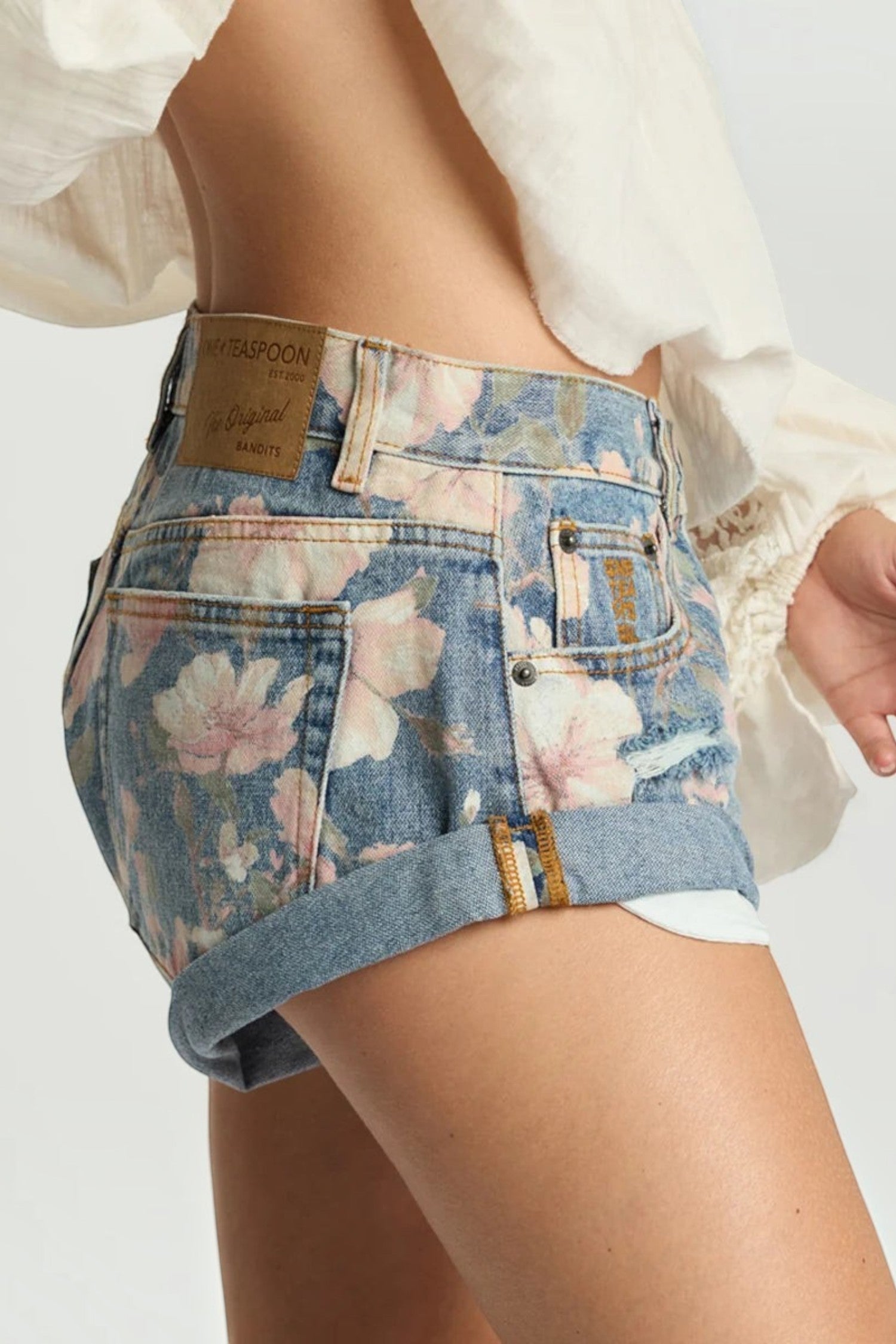 ELSHAM BOUTIQUE Bandits low waist denim shorts in Cobaine Blue with a pink floral print and rolled hem detail.