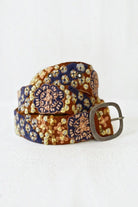 ELSHAM BOUTIQUE wool belt with blue and gold floral embroidery and a rustic metal buckle on a white background