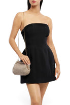 Model wearing an ELSHAM BOUTIQUE gold metallic crochet clutch with a shoulder chain and a black strapless mini dress.