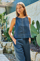 ELSHAM BOUTIQUE sleeveless linen top in gunsmoke grey with contrast stitching, worn by a model in a garden setting.