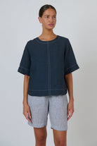 ELSHAM BOUTIQUE gunsmoke linen top with short sleeves, round neckline, and white contrast topstitching on a model