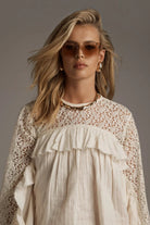 Model wearing ELSHAM BOUTIQUE ivory cotton blouse with sheer lace yoke, high neckline, and cascading front frills.