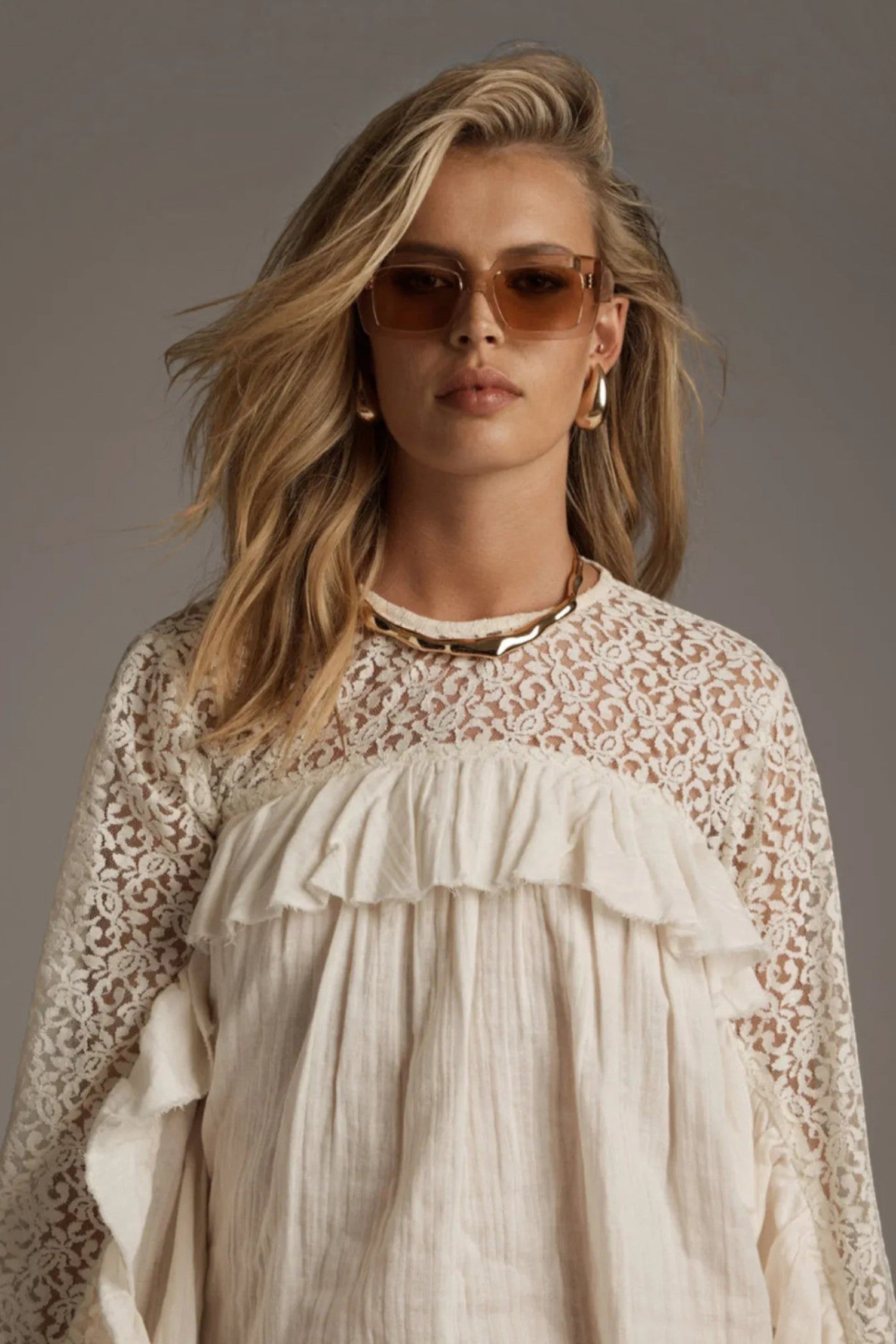 Model wearing ELSHAM BOUTIQUE ivory cotton blouse with sheer lace yoke, high neckline, and cascading front frills.