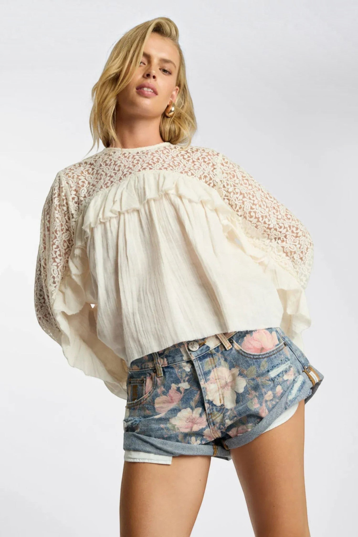 ELSHAM BOUTIQUE ivory cotton blouse with lace yoke and frill details worn by a model with floral denim shorts