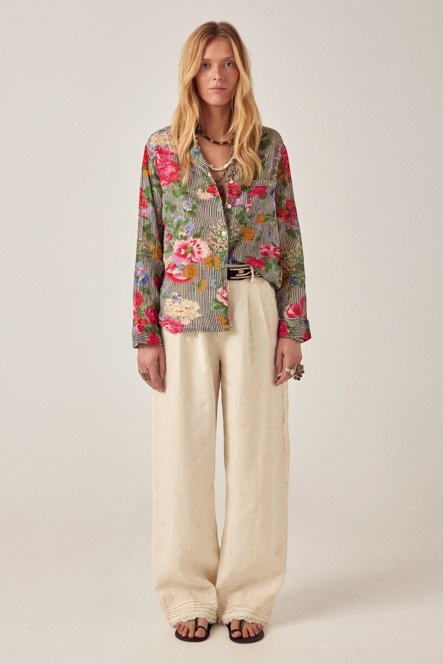Model wearing ELSHAM BOUTIQUE ivory cotton-linen Otto pants with subtle pleats and embroidered hem details