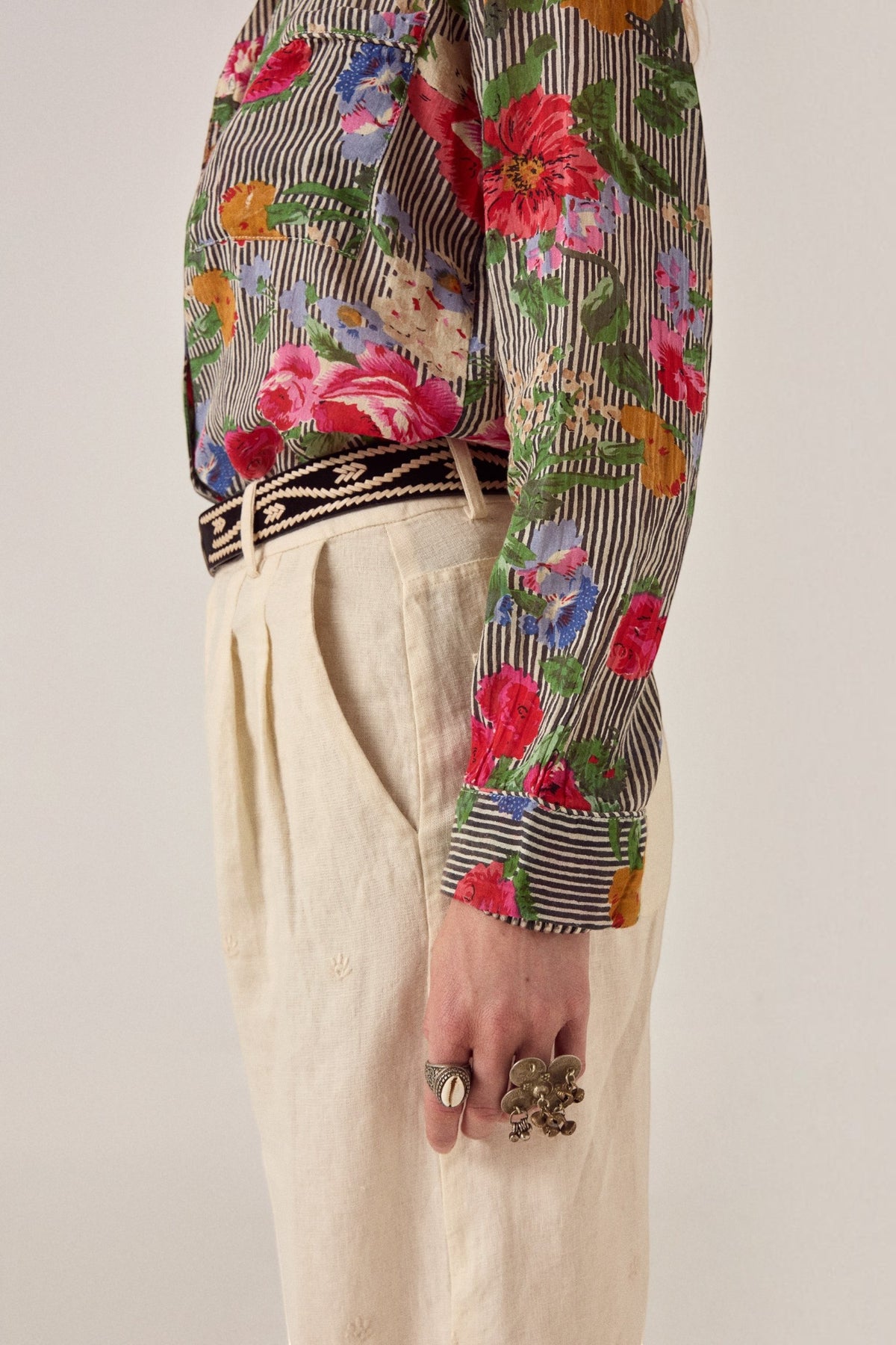 ELSHAM BOUTIQUE ivory cotton-linen Otto pants with front pleats and subtle embroidery, worn with a floral shirt.