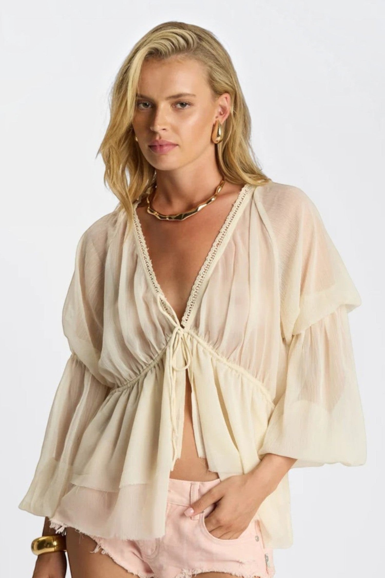 Model wearing ELSHAM BOUTIQUE ivory sheer chiffon blouse with V-neck, lace trim, and voluminous peasant sleeves.