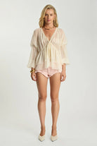 Model wearing ELSHAM BOUTIQUE ivory sheer chiffon Luminette blouse with V-neck, lace trim, and voluminous sleeves.