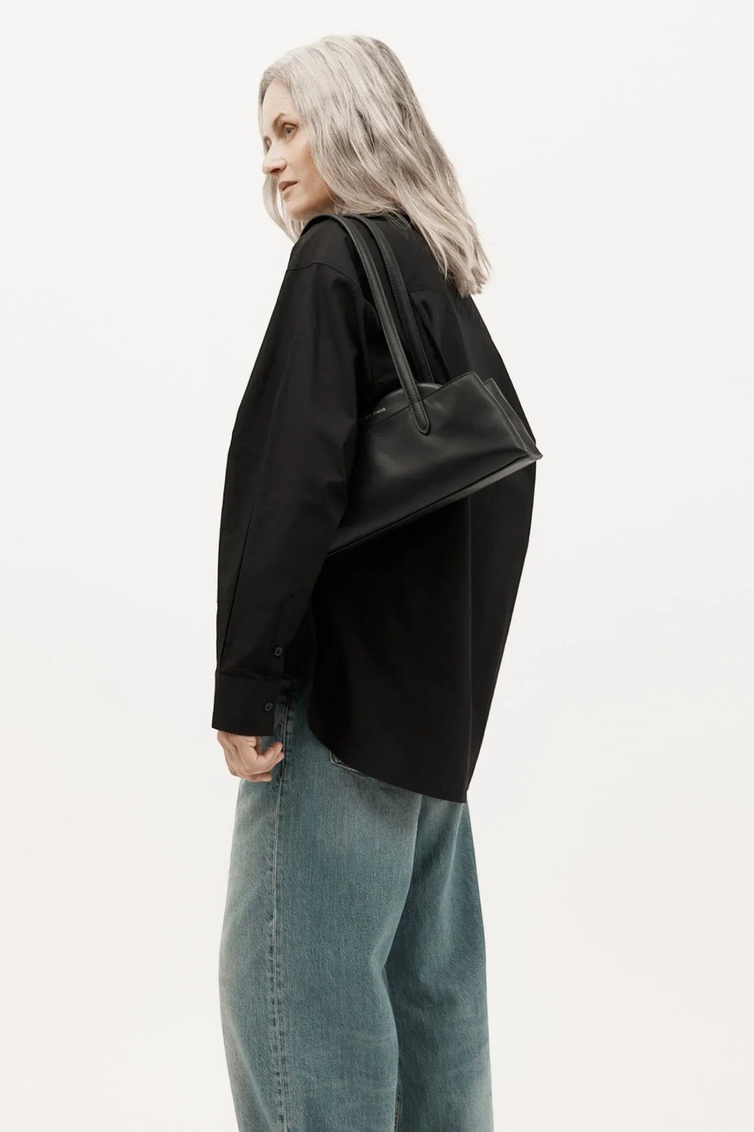 ELSHAM BOUTIQUE Mini Vault Tote in black calf nappa leather with brass hardware, worn over the shoulder by a model.