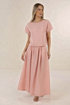 Model wearing ELSHAM BOUTIQUE musk pink linen-tencel midi skirt with A-line silhouette and side pockets