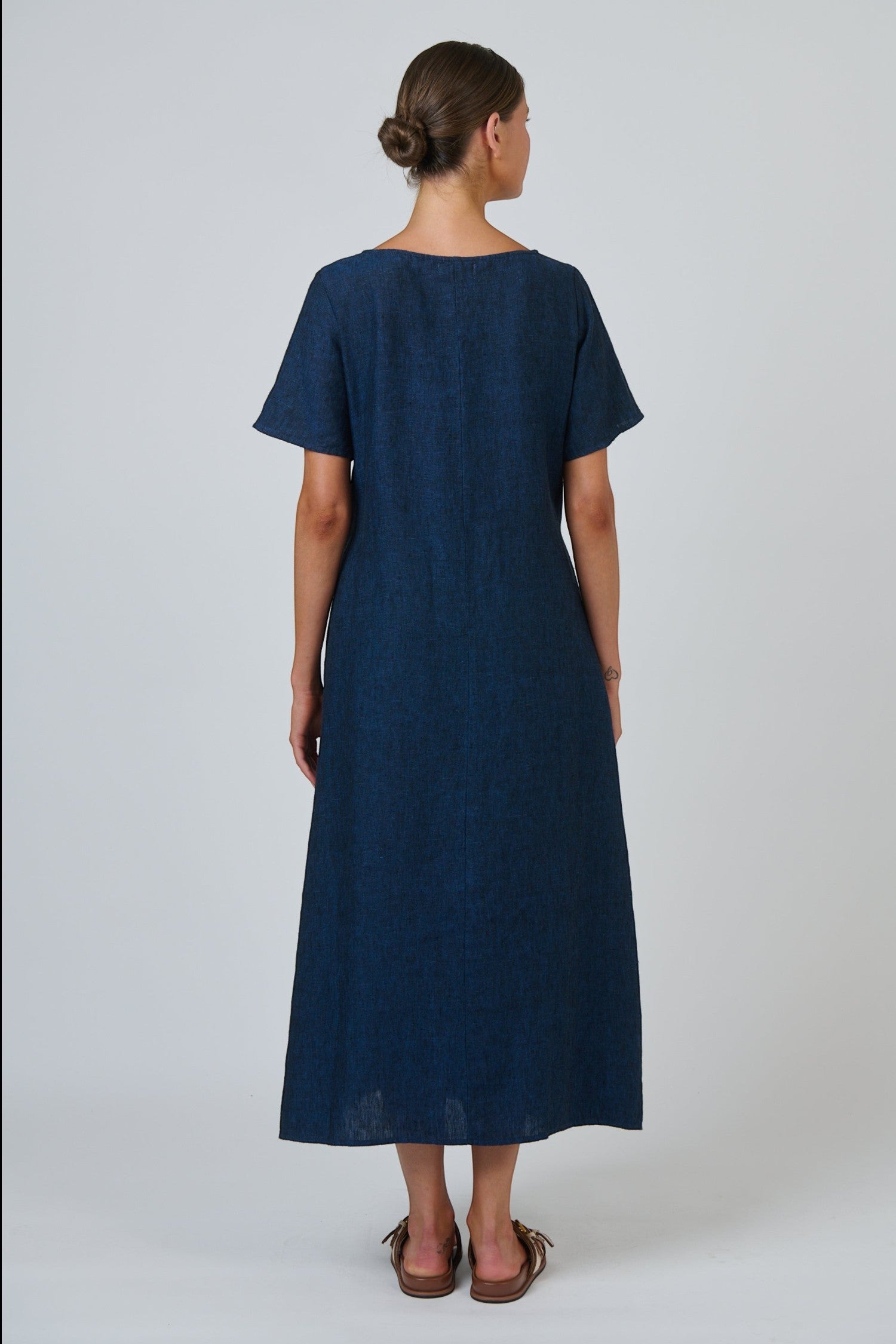 Back view of a woman wearing an ELSHAM BOUTIQUE navy blue 100% linen midi dress with short sleeves and A-line cut.
