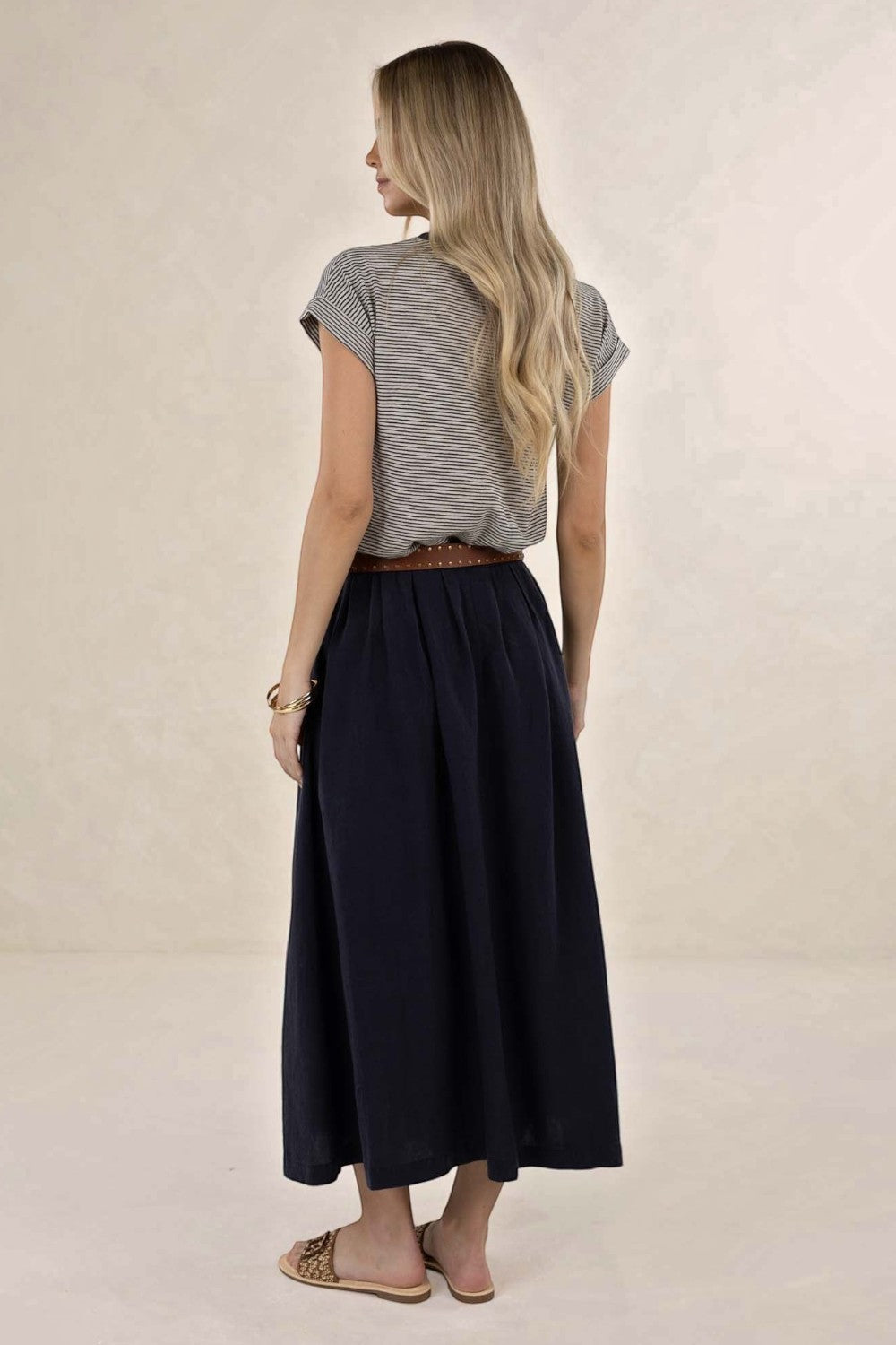 Back view of a woman wearing an ELSHAM BOUTIQUE navy linen-tencel midi skirt with an A-line silhouette and pockets.