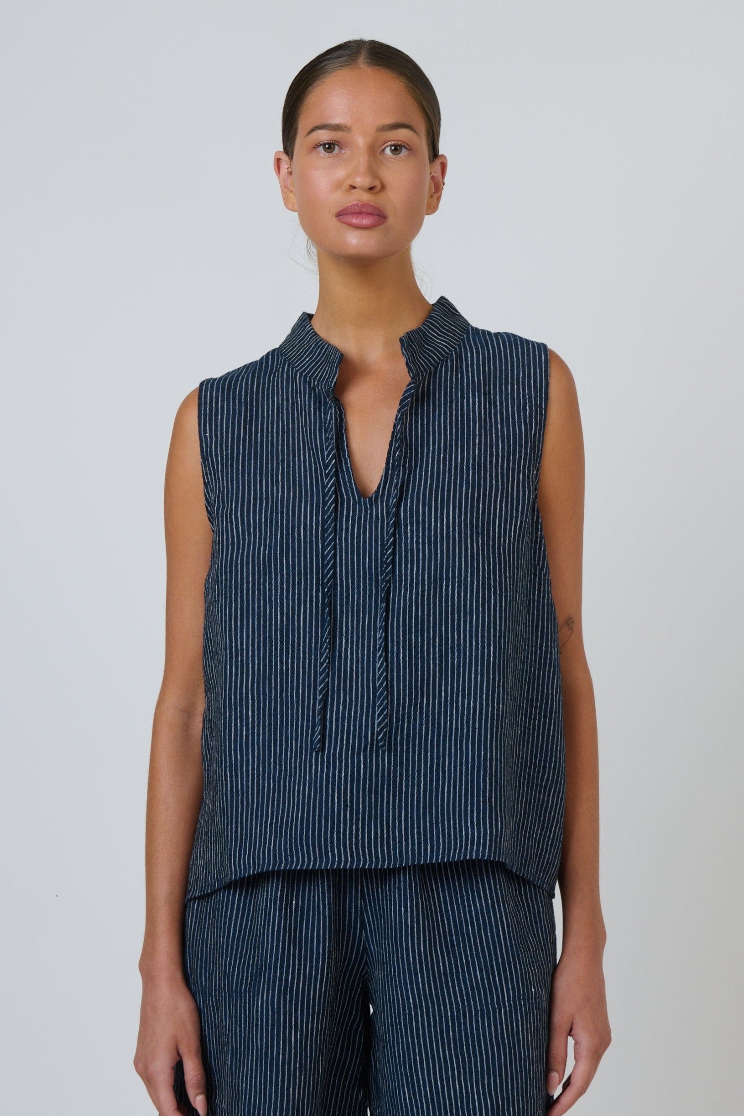 ELSHAM BOUTIQUE navy pinstripe linen sleeveless top with a V-neckline and adjustable neck tie on a model
