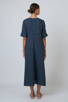 Back view of a woman wearing an ELSHAM BOUTIQUE navy blue striped linen A-line midi dress with elbow-length sleeves.