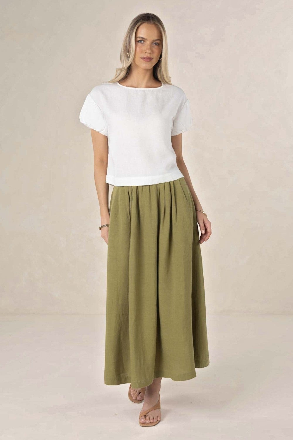 Model wearing an ELSHAM BOUTIQUE olive green linen-tencel midi skirt with an A-line silhouette and side pockets.